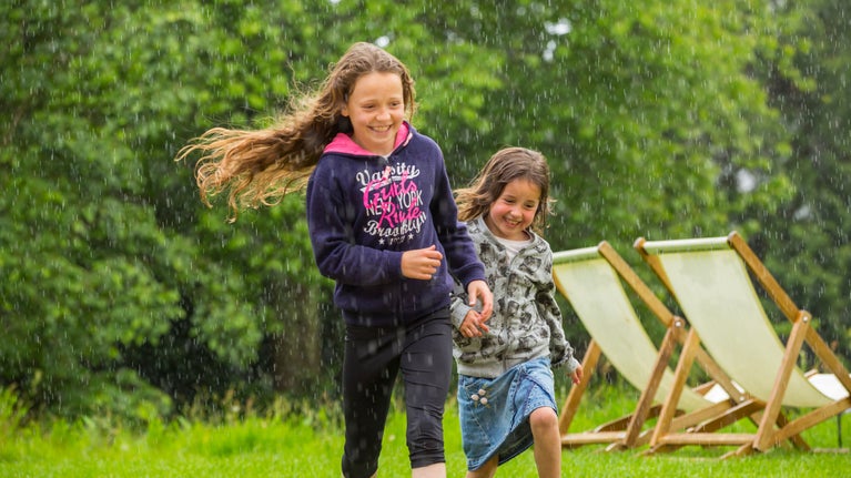 Children playing in the garden during a rain shower at Greenway, Devon